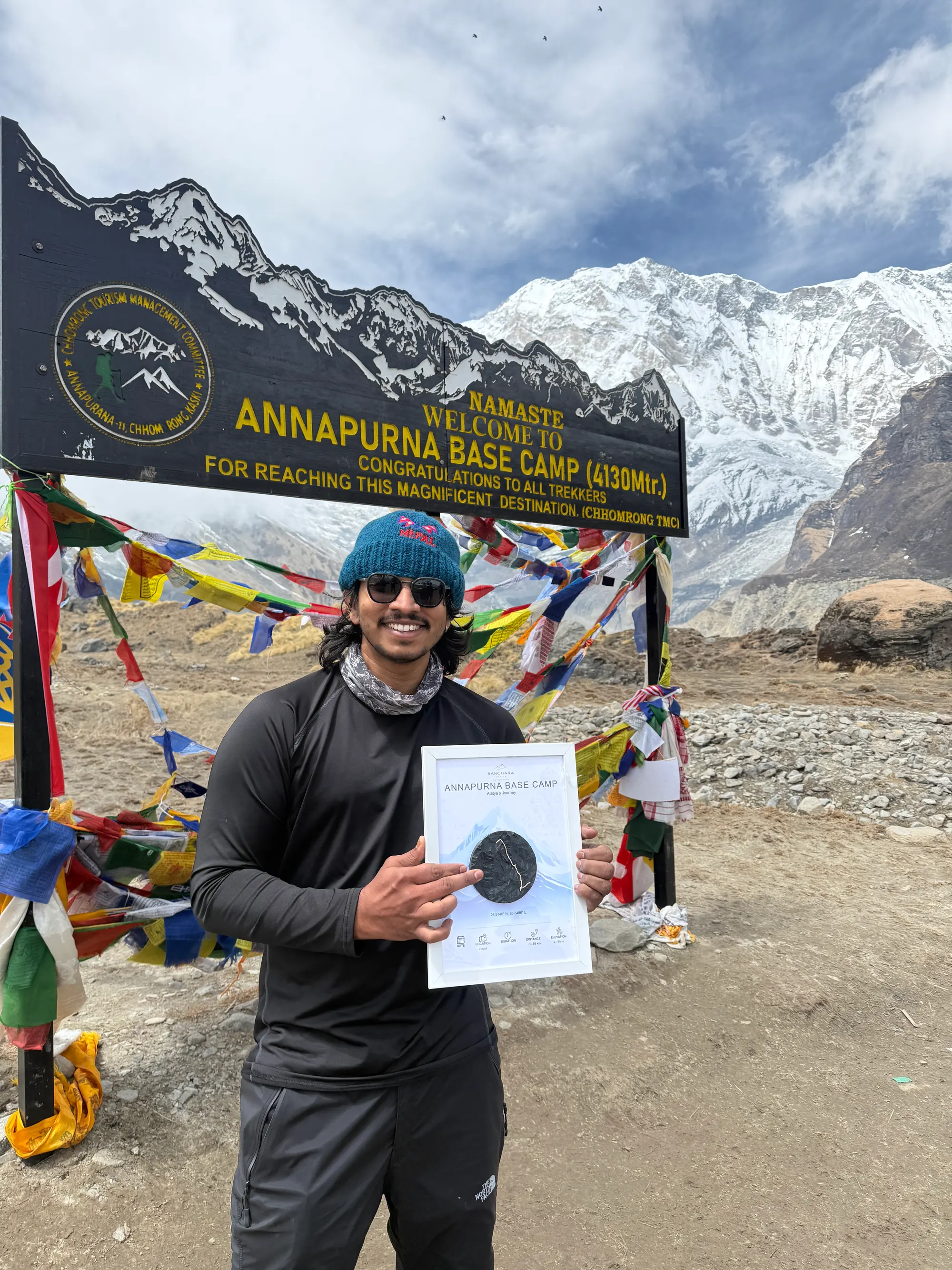 Aditya at the Annapurna Base Camp sign, holding a trail map